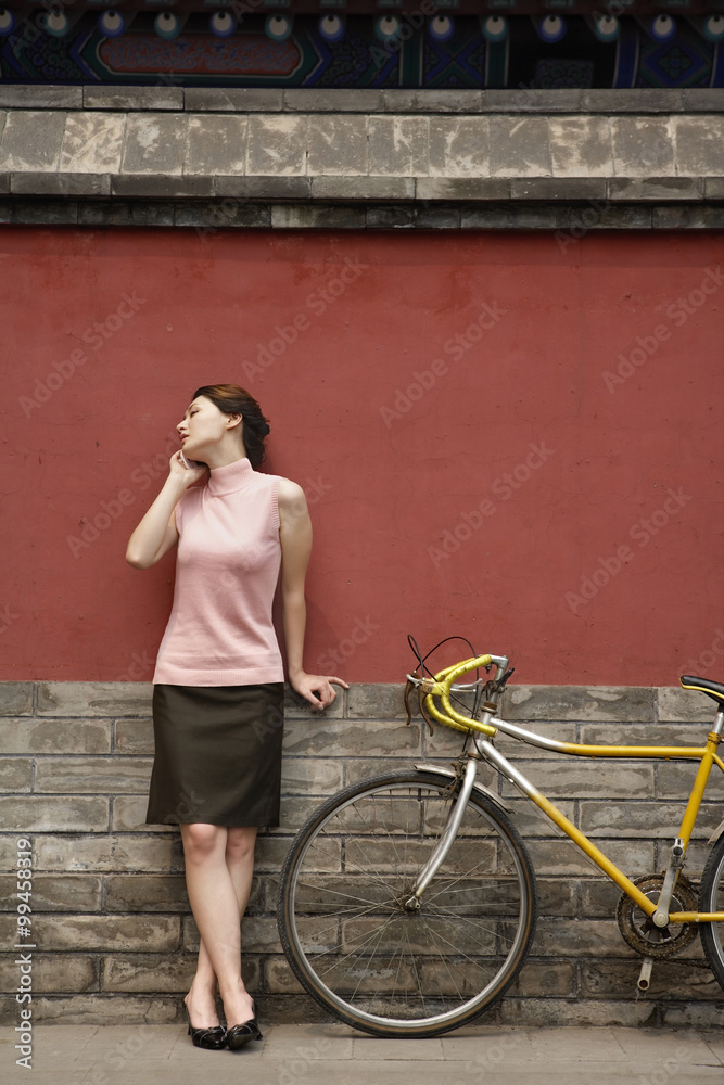 年轻女子靠在墙上讲手机
