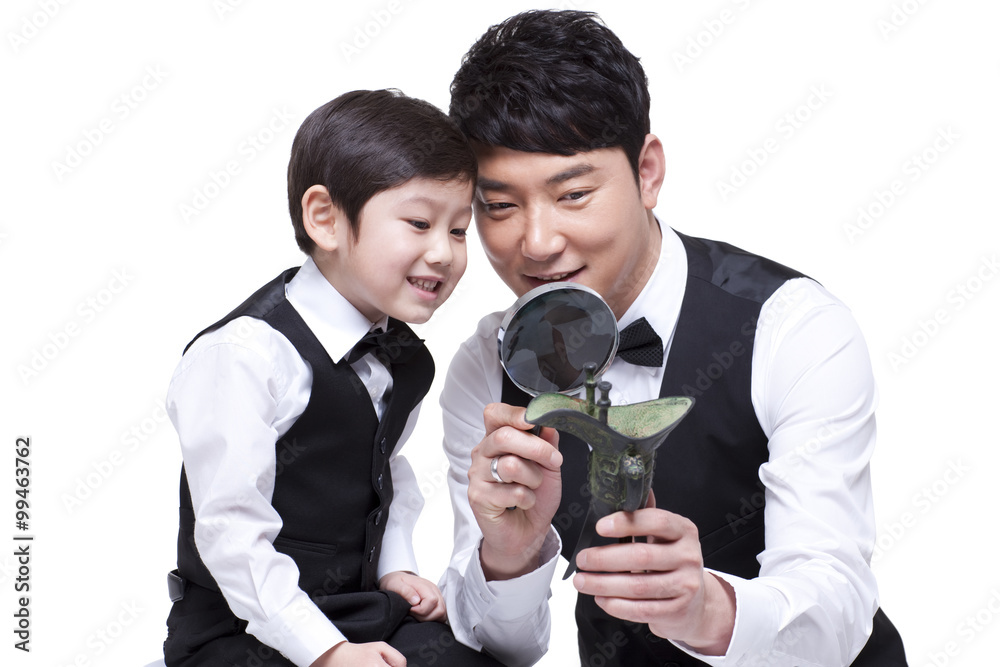 Father and son examining Chinese bronze ware through magnifying glass