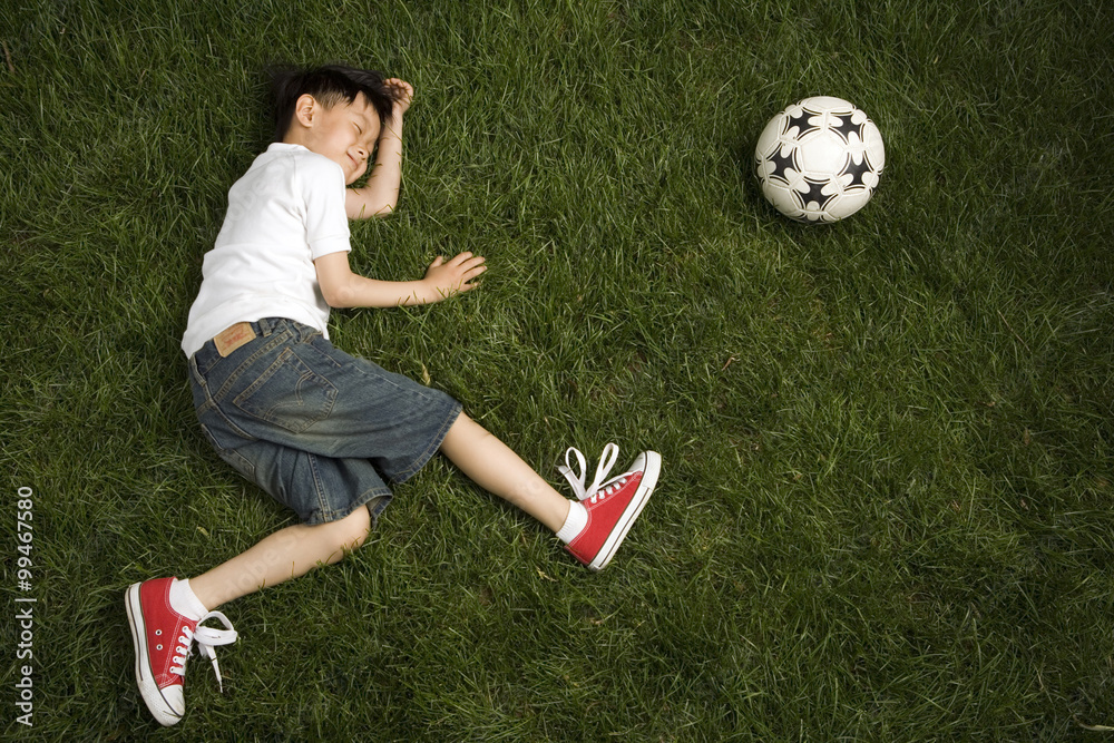 草地上在足球旁边装死的男孩