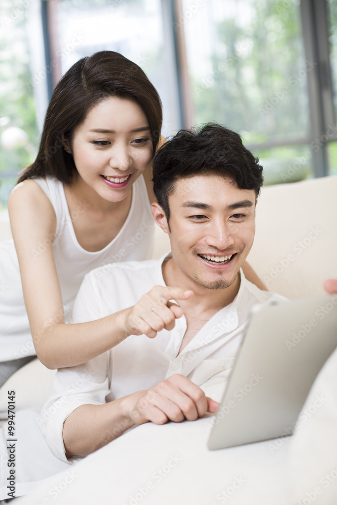 快乐的年轻夫妇在客厅使用数字平板电脑