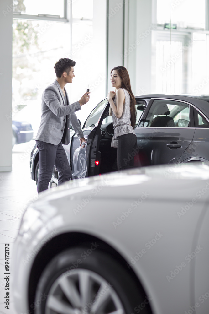 Young couple buying car in showroom