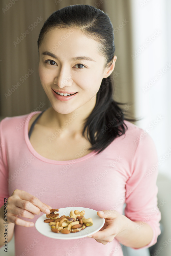 Happy young woman eating nuts