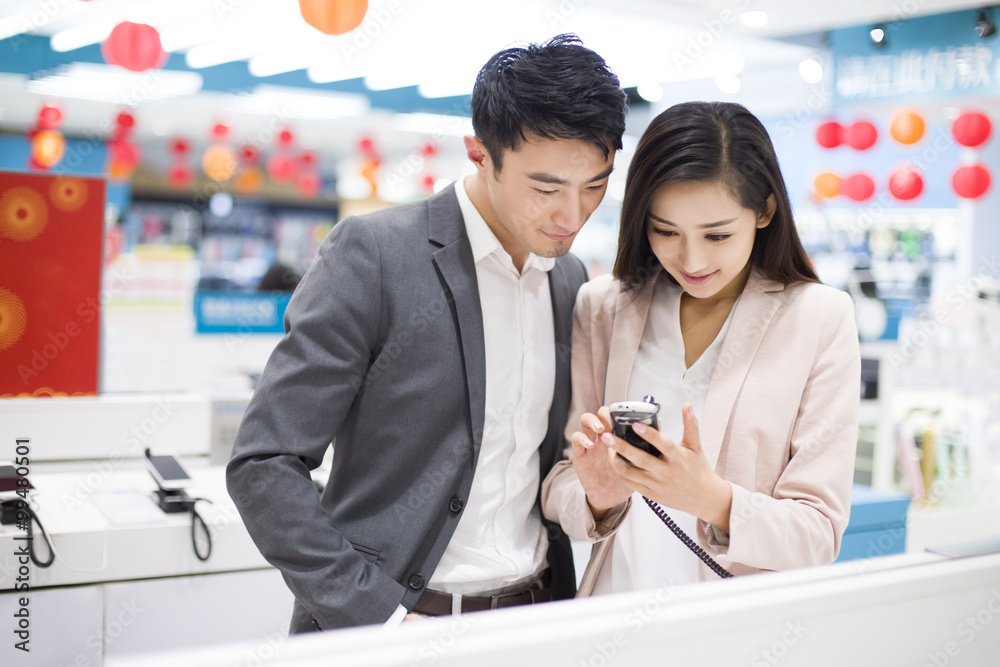 Young couple looking at smart phone in electronics store