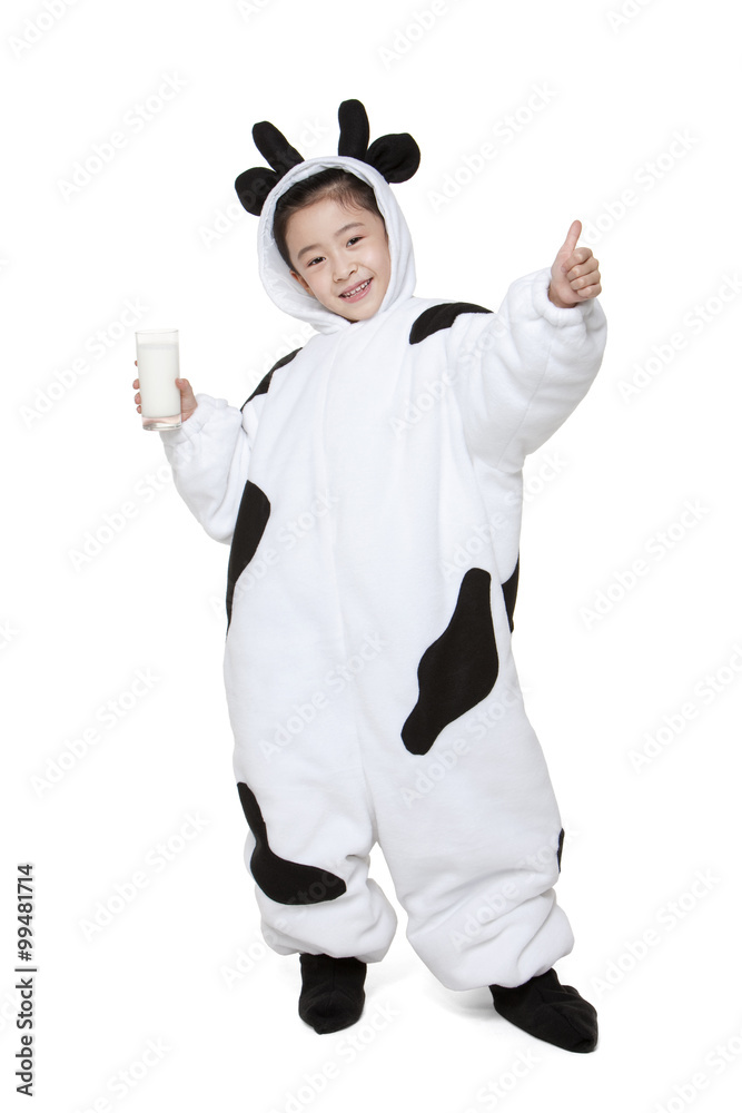 可爱的女孩穿着奶牛服装，拿着一杯牛奶竖起大拇指