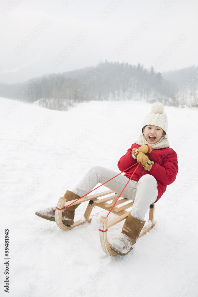 快乐女孩在雪橇上滑行