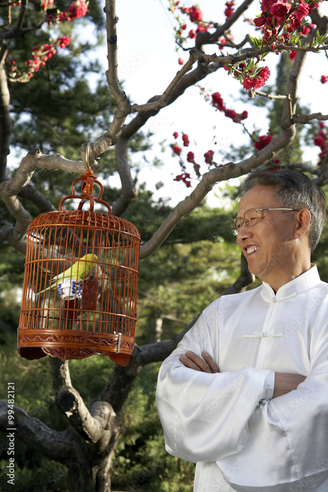 Chinese Man Looking At Bird In Cage