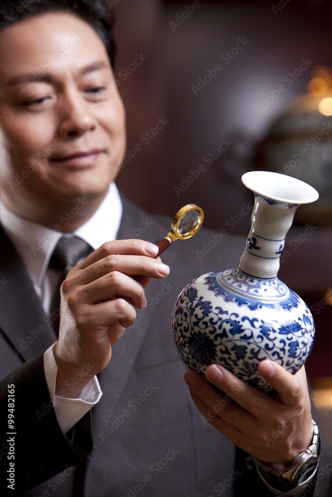 成熟的商人欣赏一个古董中国花瓶