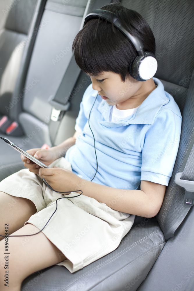 可爱的男孩在车里用智能手机听音乐