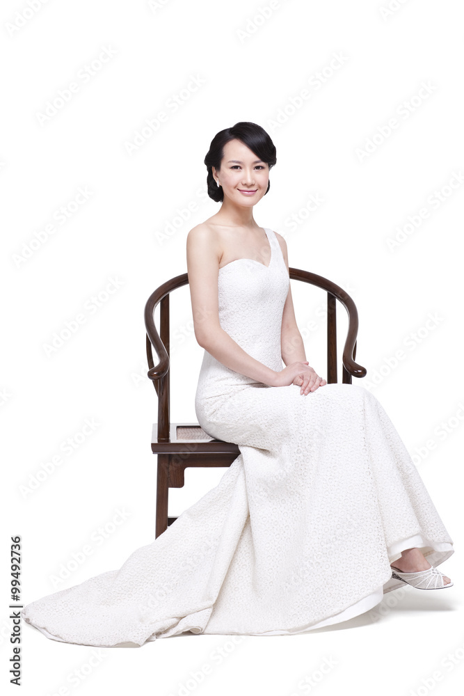优雅的年轻女子坐在中式明代木扶手椅上