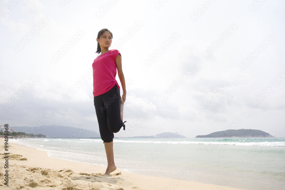 Young woman stretching by the sea