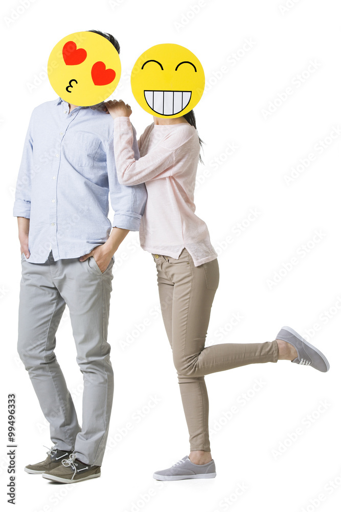 Young couple with cartoon emoticon faces in front of their faces