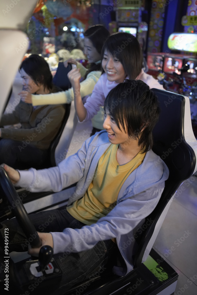 青少年在街机上玩赛车游戏