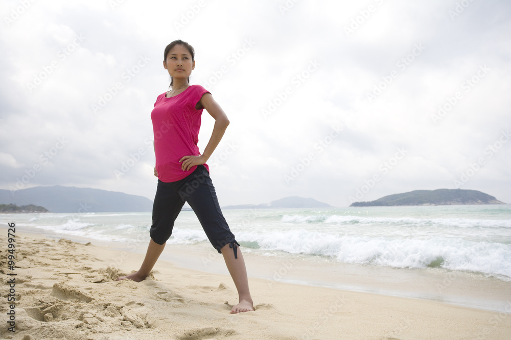 Young woman stretching by the sea