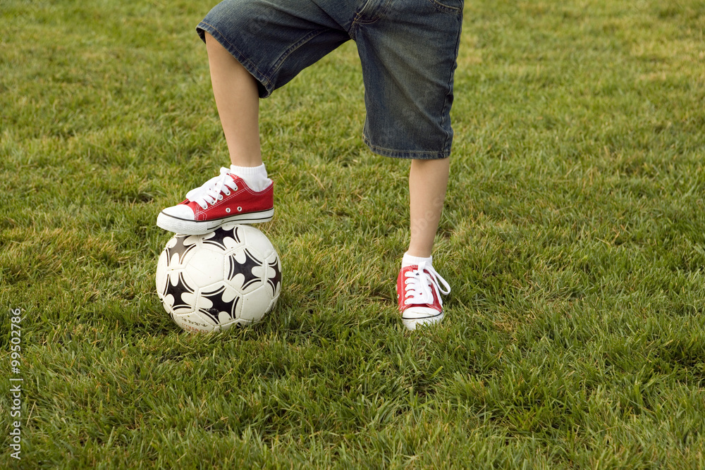 Boy Standing With One Foot On Soccer Ball