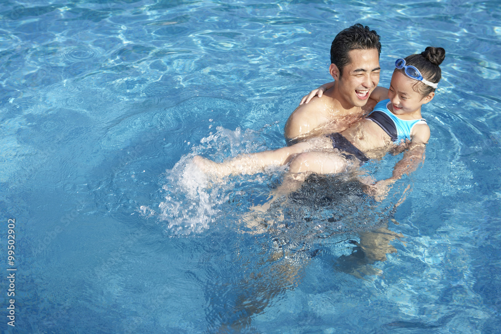 父亲和女儿在游泳池游泳