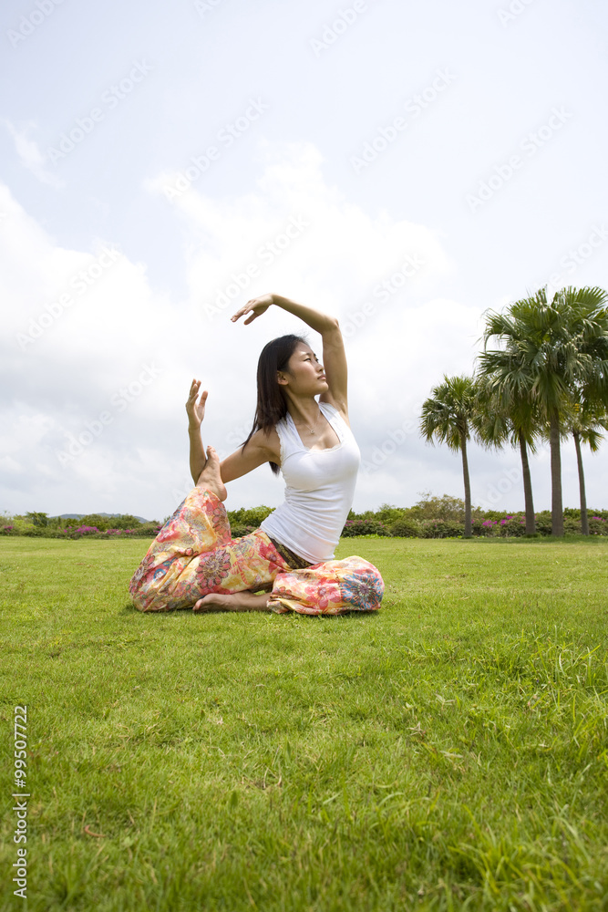 Young woman doing yoga in grass