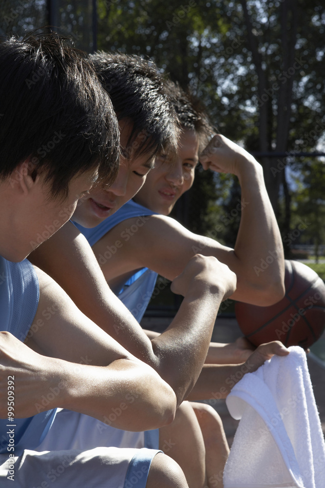 年轻人在篮球场旁比较肌肉