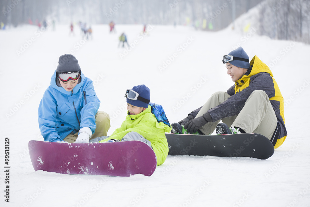 Young parents teaching son to snowboard