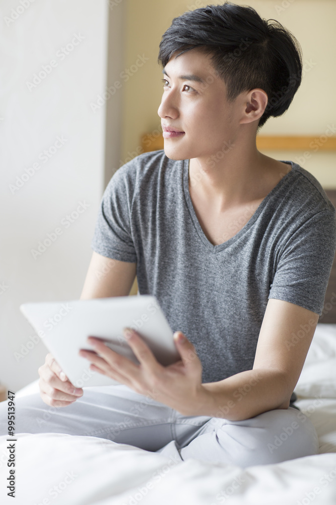 Young man using digital tablet on bed