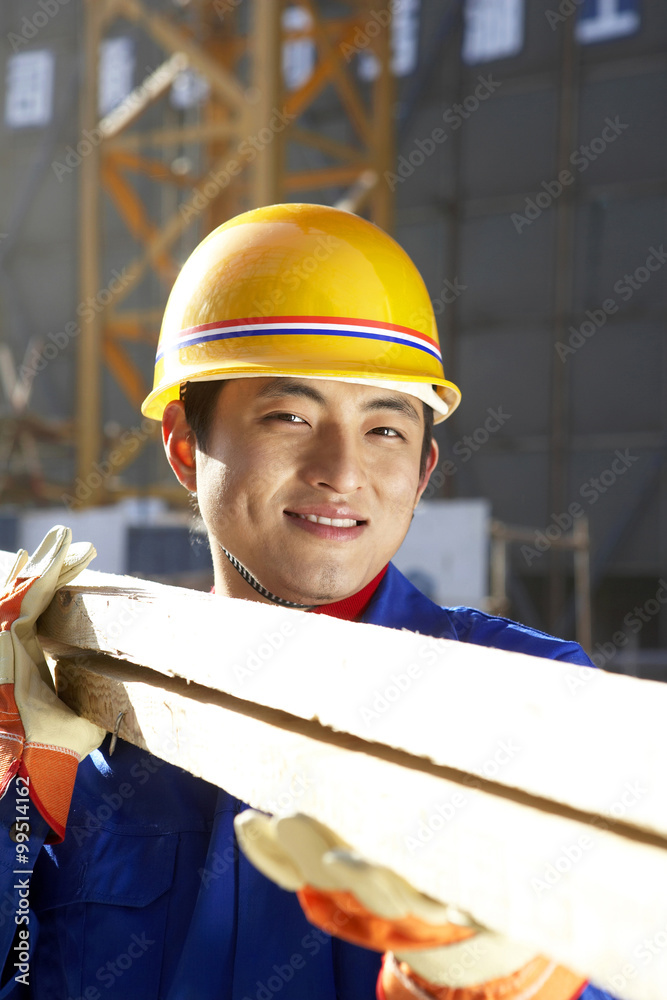 建筑工地上戴着安全帽和木板的人