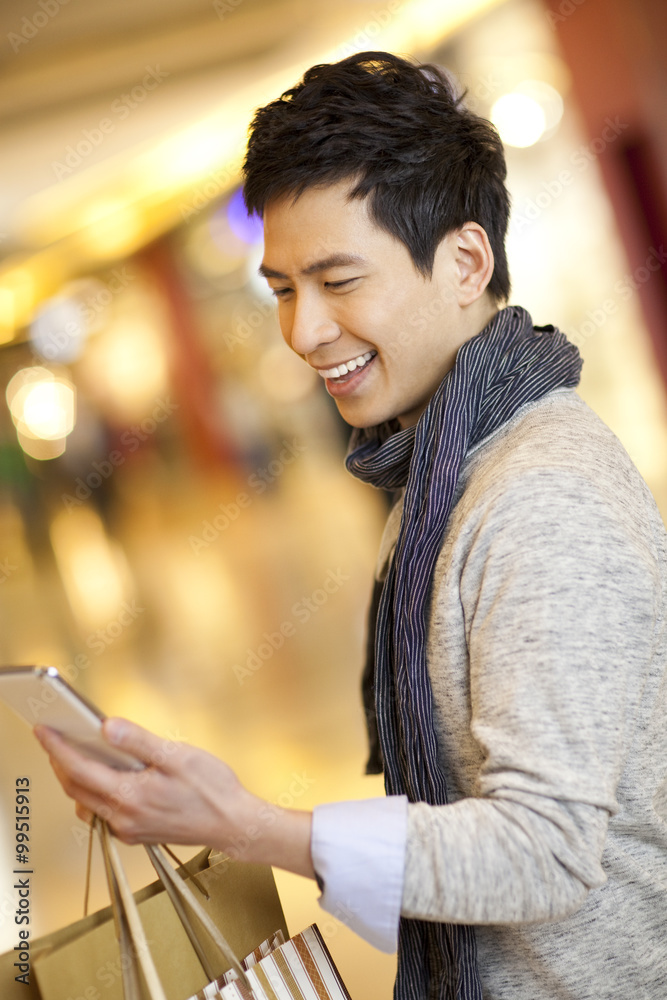 Young man with smart phone in shopping mall