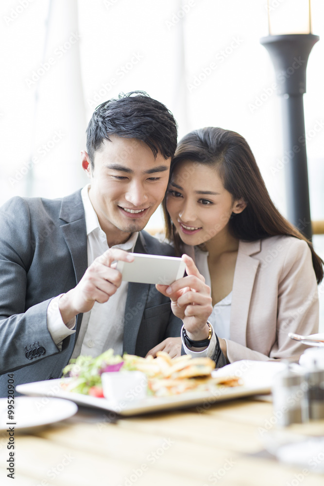 Young couple photographing in restaurant 