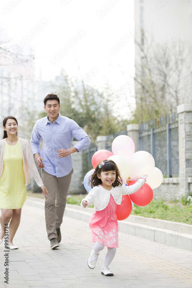 快乐的年轻家庭用气球奔跑