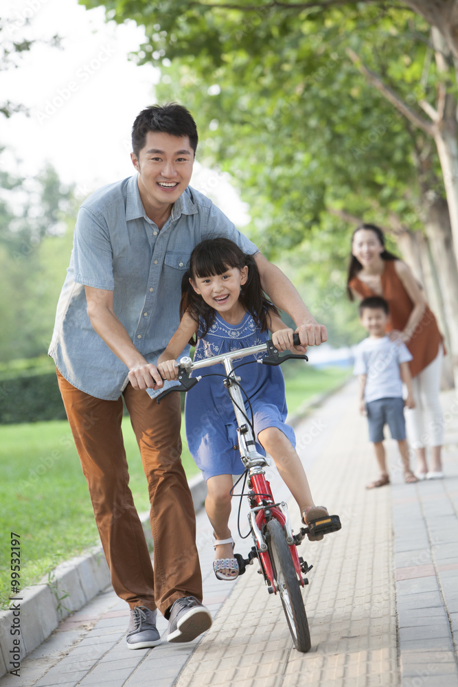 年轻的父亲教女儿骑自行车