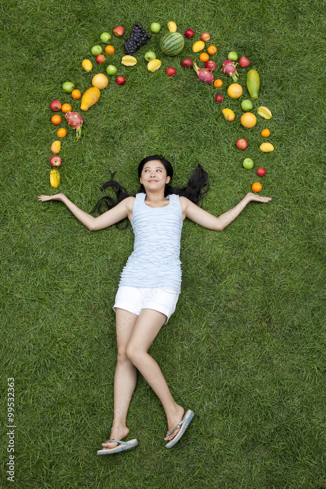 草地上结着新鲜水果的年轻女人