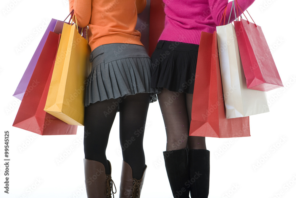 两名年轻女子举起购物袋的后视图