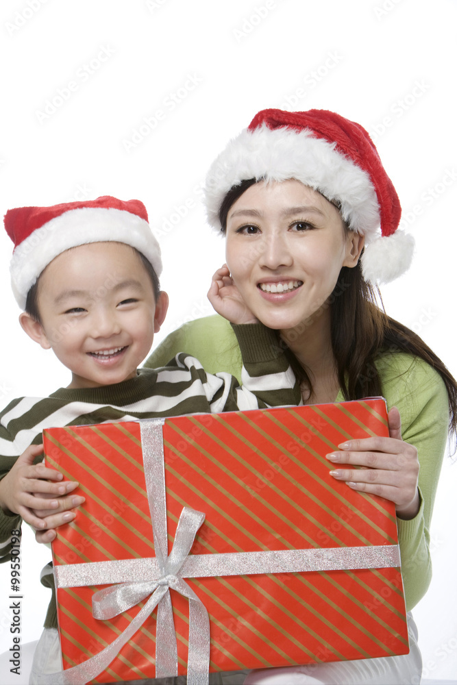Mother and son with Santa hats holding gift box