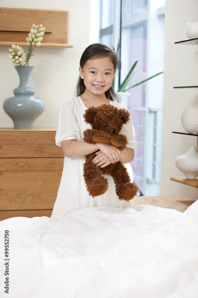 卧室里的小女孩手里拿着泰迪熊