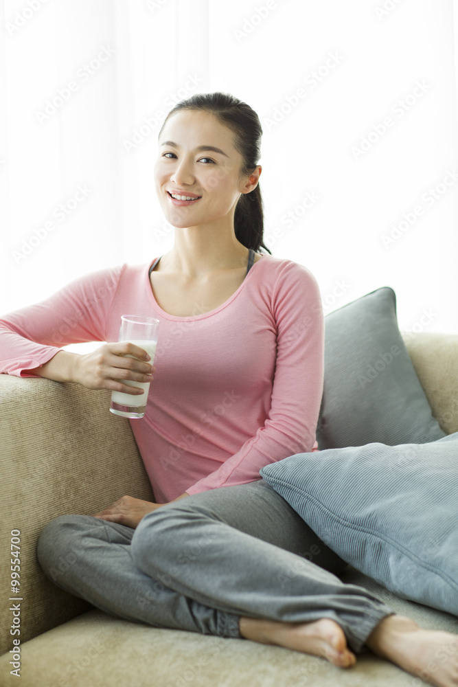 快乐的年轻女人拿着一杯牛奶