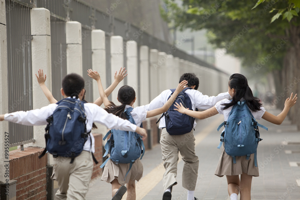 上学路上穿着校服的活泼学童的后视图