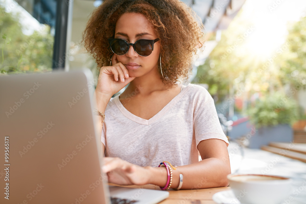 时尚的年轻女孩在户外咖啡馆使用笔记本电脑