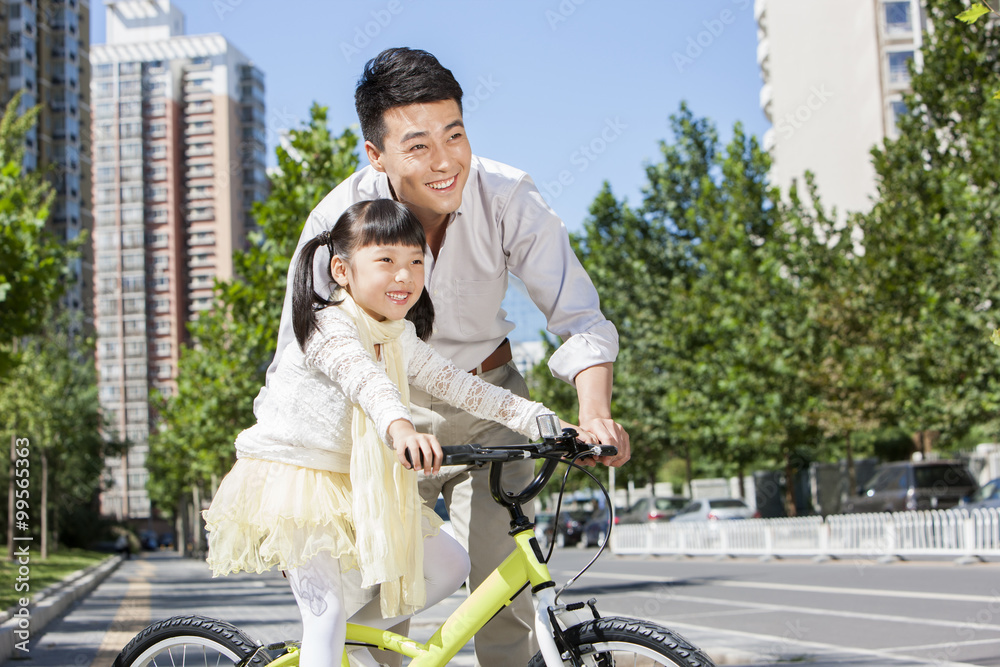 好心的年轻父亲在街上教女儿骑自行车