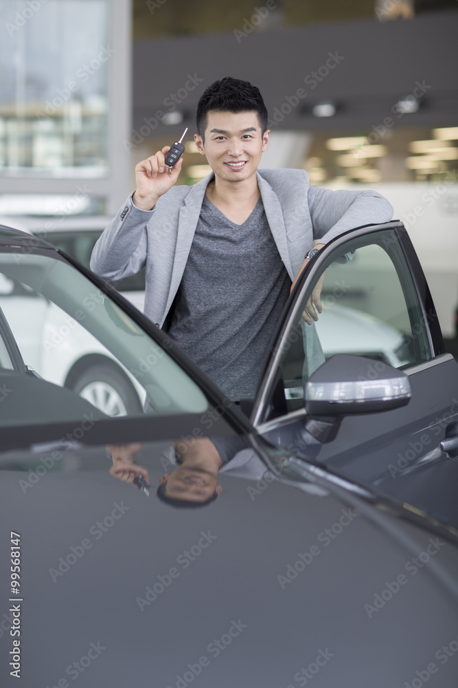 Young man buying car in showroom