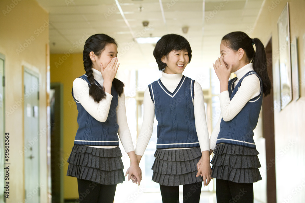三名女学生在学校走廊大笑