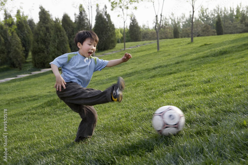 小男孩在公园里快乐地踢足球