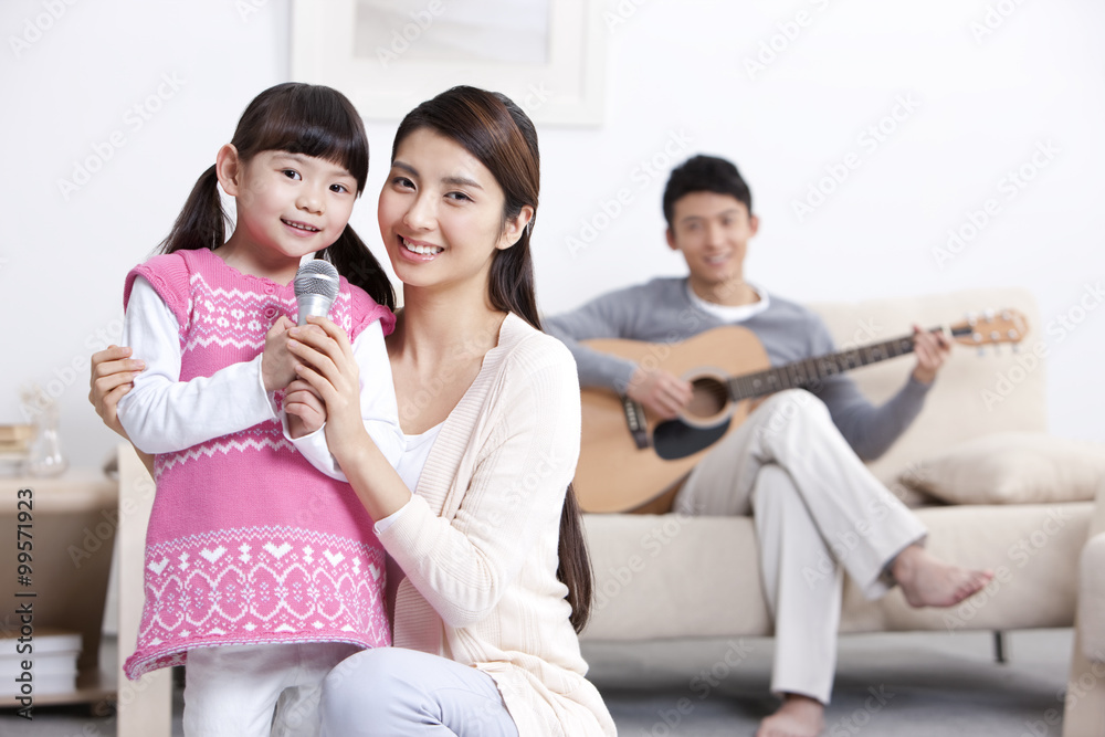 快乐的年轻家庭在客厅里弹吉他唱歌