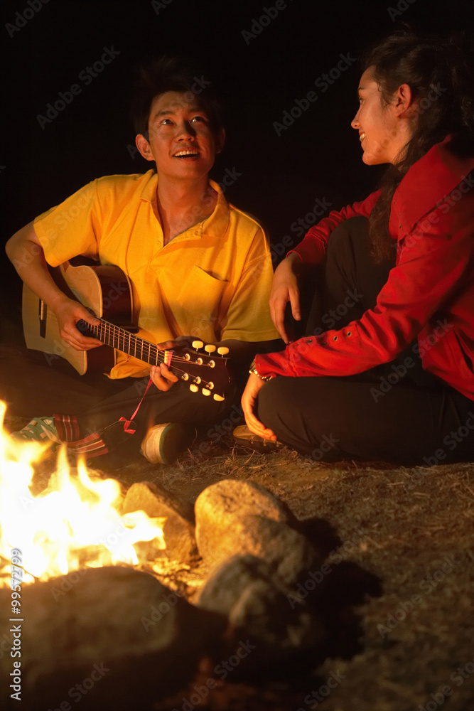 Young Couple Sitting By Campfire