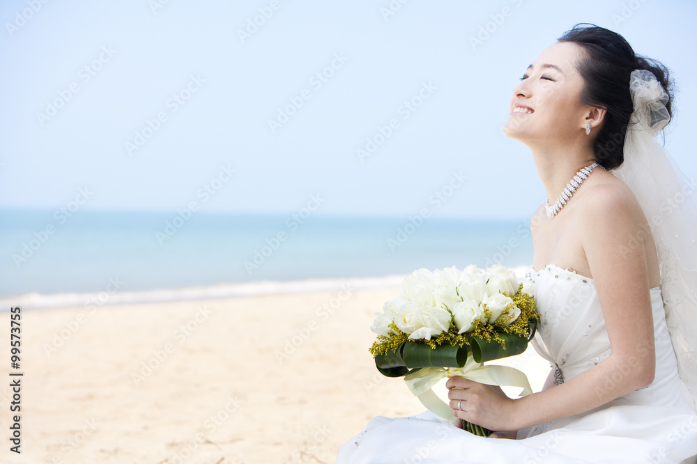 快乐的新娘坐在海滩上