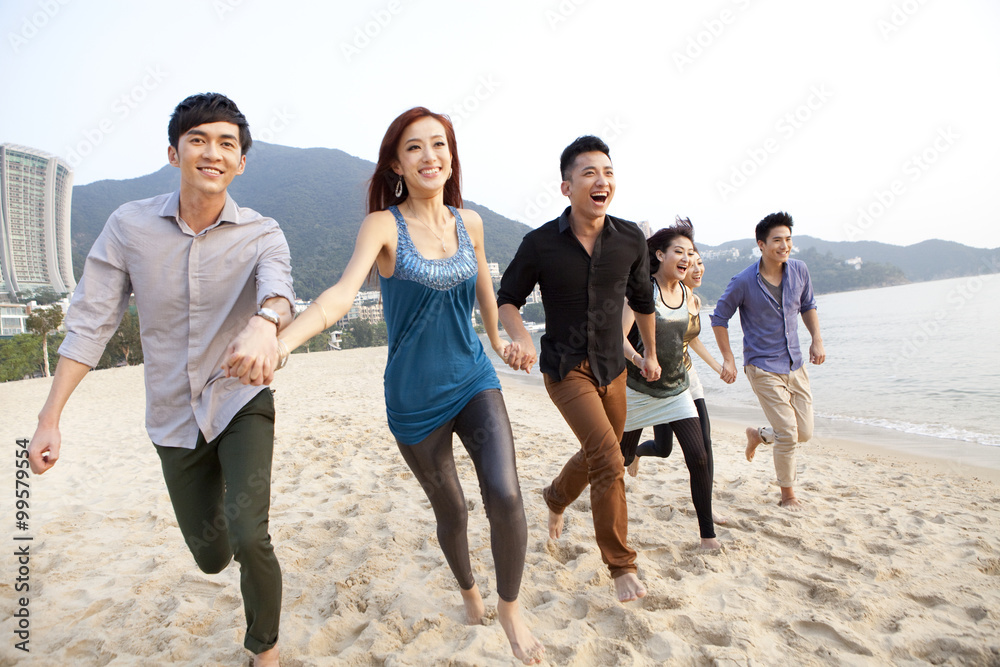 兴奋的年轻人在香港浅水湾海滩上手挽着手奔跑