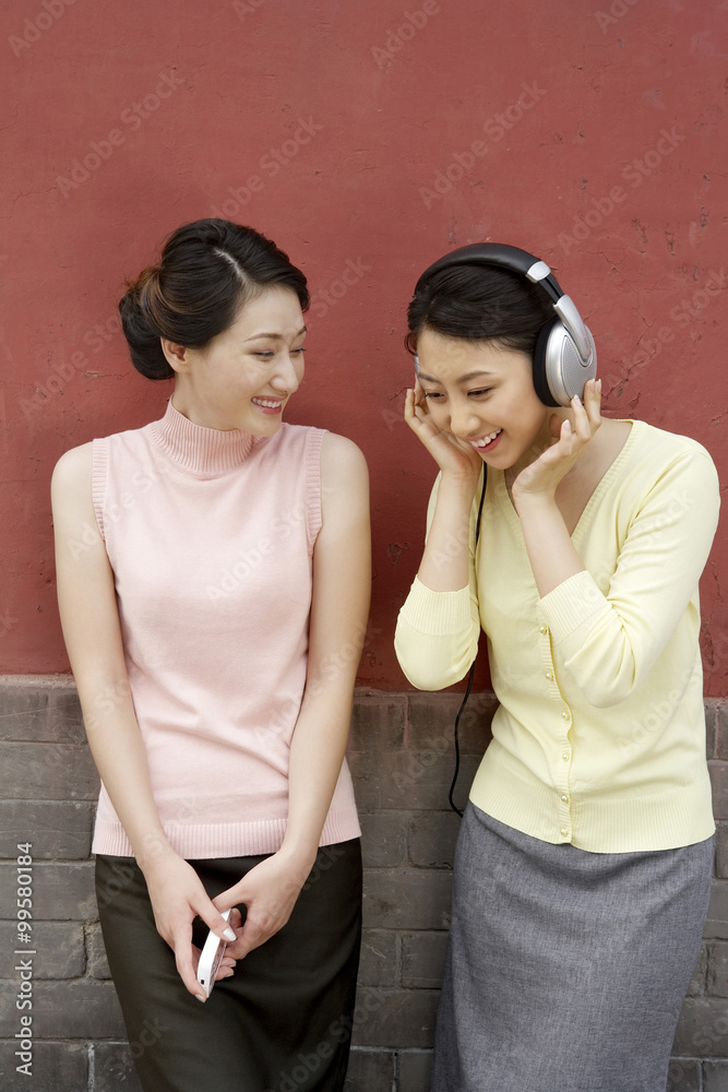 两个年轻女人听音乐笑