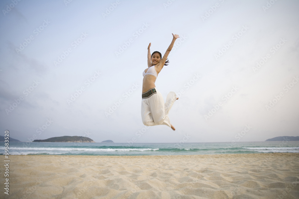 年轻女子在海滩上跳跃