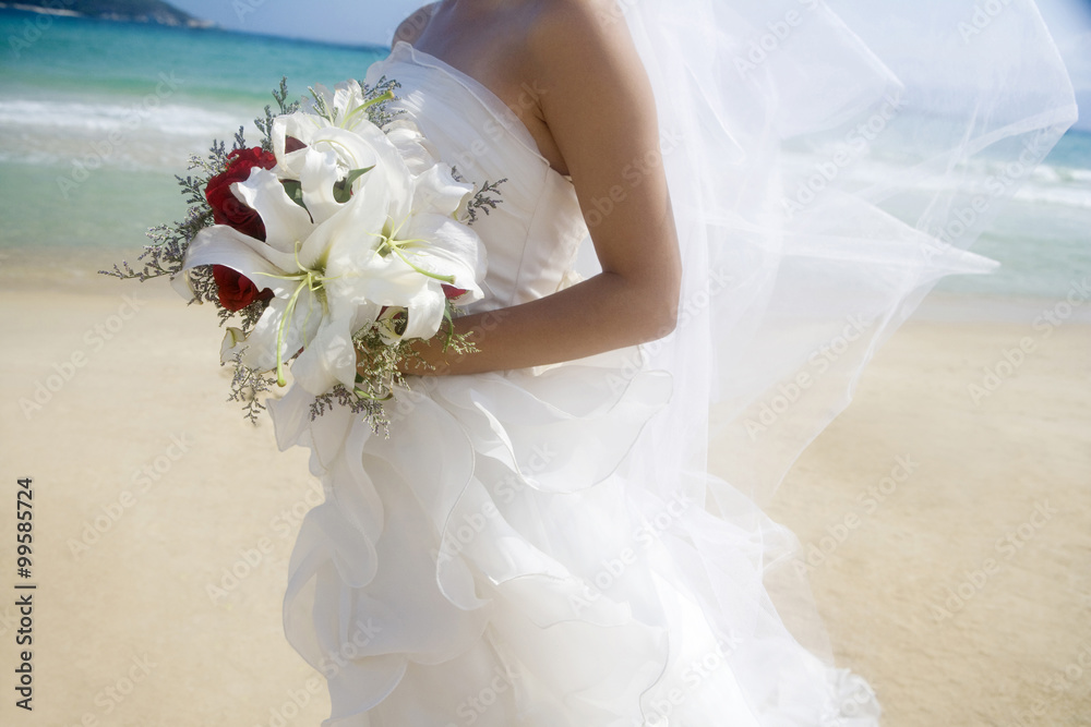 新娘在海滩上拿着一束鲜花