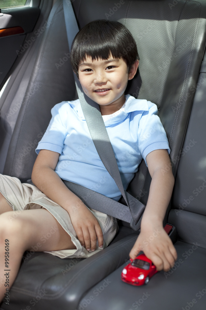 坐在后座玩玩具车的可爱小男孩