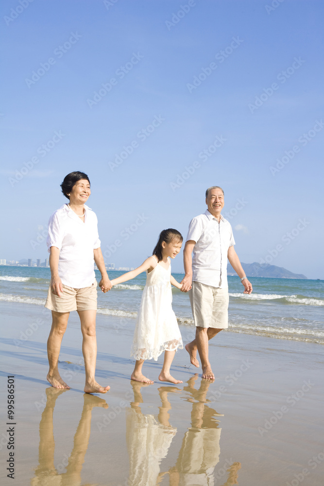 爷爷奶奶和孙女在海滩上散步