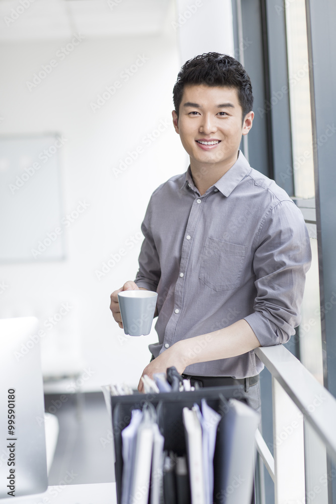 Young businessman drinking coffee in office