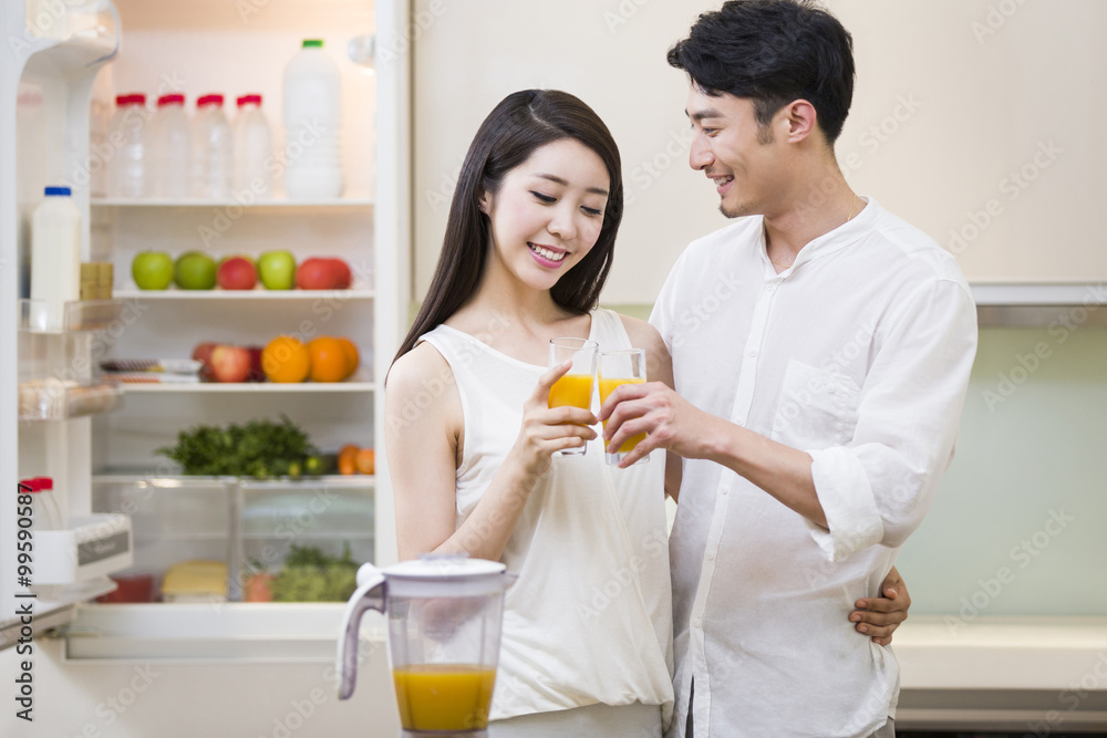 年轻夫妇在厨房里拿着橙汁
